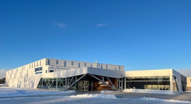 A modern, large-scale institutional building with a contemporary geometric design featuring light-colored exterior panels and angular architecture.